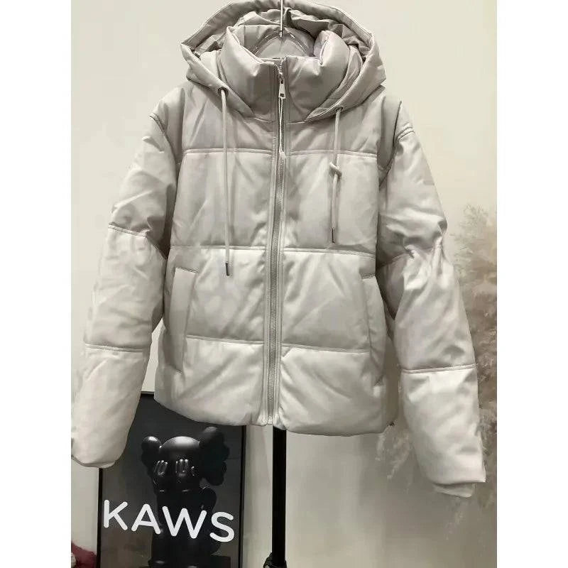 Jaqueta puffer feminina para inverno, cor bege claro, com capuz e zíper aparente, exibindo a textura suave e o acolchoamento premium para aquecimento elegante.