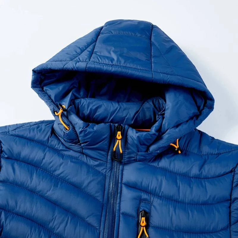 Close-up da parte superior da jaqueta puffer masculina azul royal, destacando o capuz com cordões ajustáveis laranja, o zíper frontal preto e o bolso do peito com zíper laranja. Detalhes de alta qualidade que garantem funcionalidade e um design arrojado.
