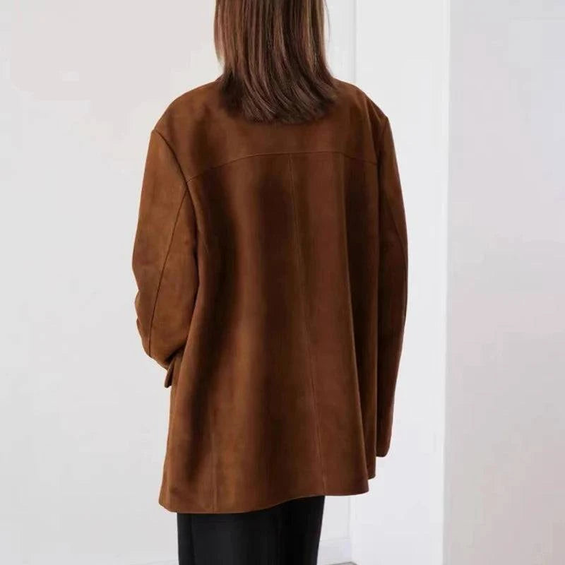 Parte traseira da jaqueta retro feminina de pele de carneiro marrom, exibindo a textura aveludada do material e o corte reto elegante, destacando a qualidade e o luxo discreto da peça.