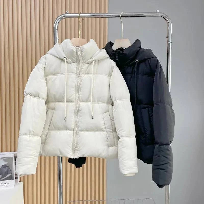 Duas jaquetas puffer femininas para inverno, uma creme e uma preta, ambas com capuz, zíperes e acolchoamento elegante, exibindo versatilidade e estilo exclusivo para o frio.