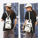Mulher de costas e lateral usando mochila transversal pequena de nylon creme com detalhes em preto, em estilo casual urbano com camiseta e boné.
