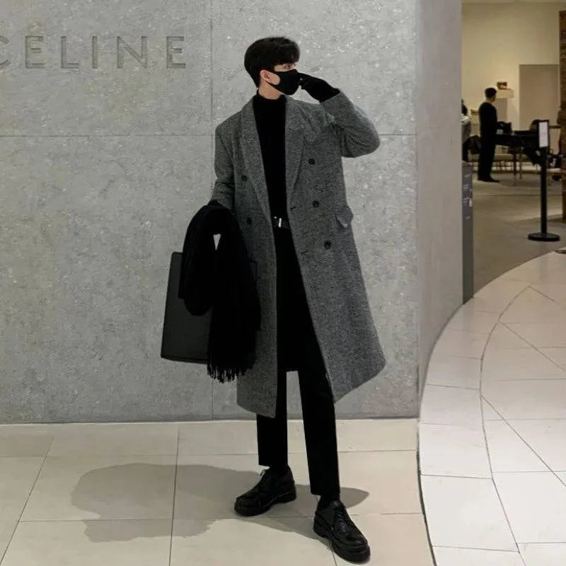 Homem usando Sobretudo Masculino Longo Cinza Imperium com abotoamento duplo em ambiente moderno. Ideal para moda masculina outono/inverno.