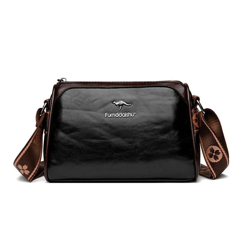 Shoulder Bag Bolsa Feminina de Couro preta, com design de dois tons e alça estampada larga. Logo metálico de canguru. Elegante e versátil.