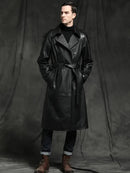 Sobretudo masculino de couro preto longo com gola aberta, vestido com gola rulê e botas marrons.
