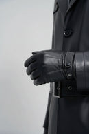 Detalhe de luva e cinto de couro do sobretudo masculino preto, com botão e fivela visíveis