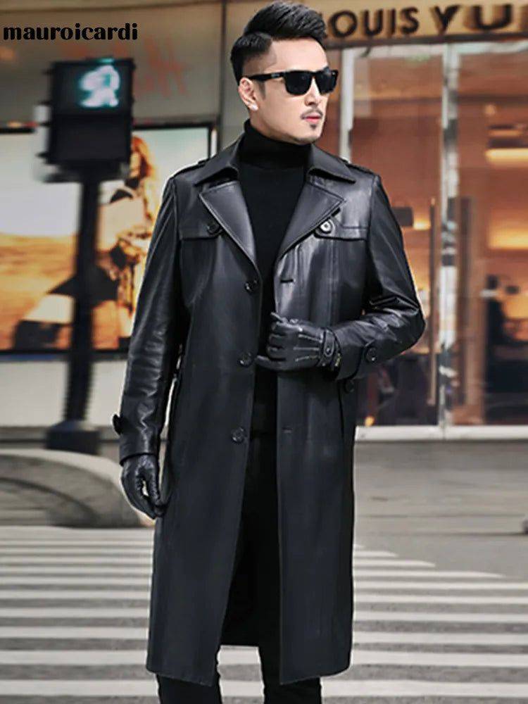 Sobretudo masculino Zellum longo em couro genuíno preto, com gola alta, luvas e óculos escuros, em frente a loja "Louis Vuitton", evocando privilégio e estilo.
