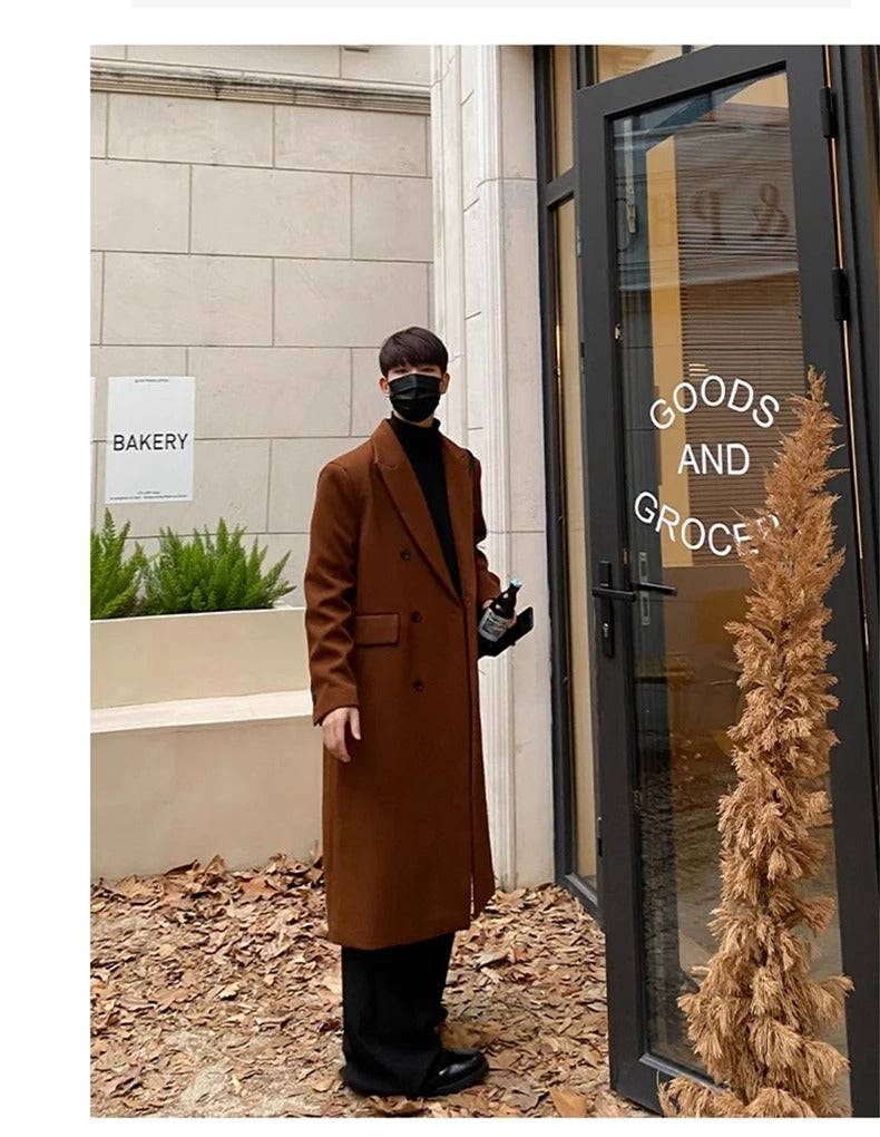 Sobretudo masculino longo social marrom em ambiente externo com folhas secas, estilo elegante para o outono. Ideal para moda masculina refinada.