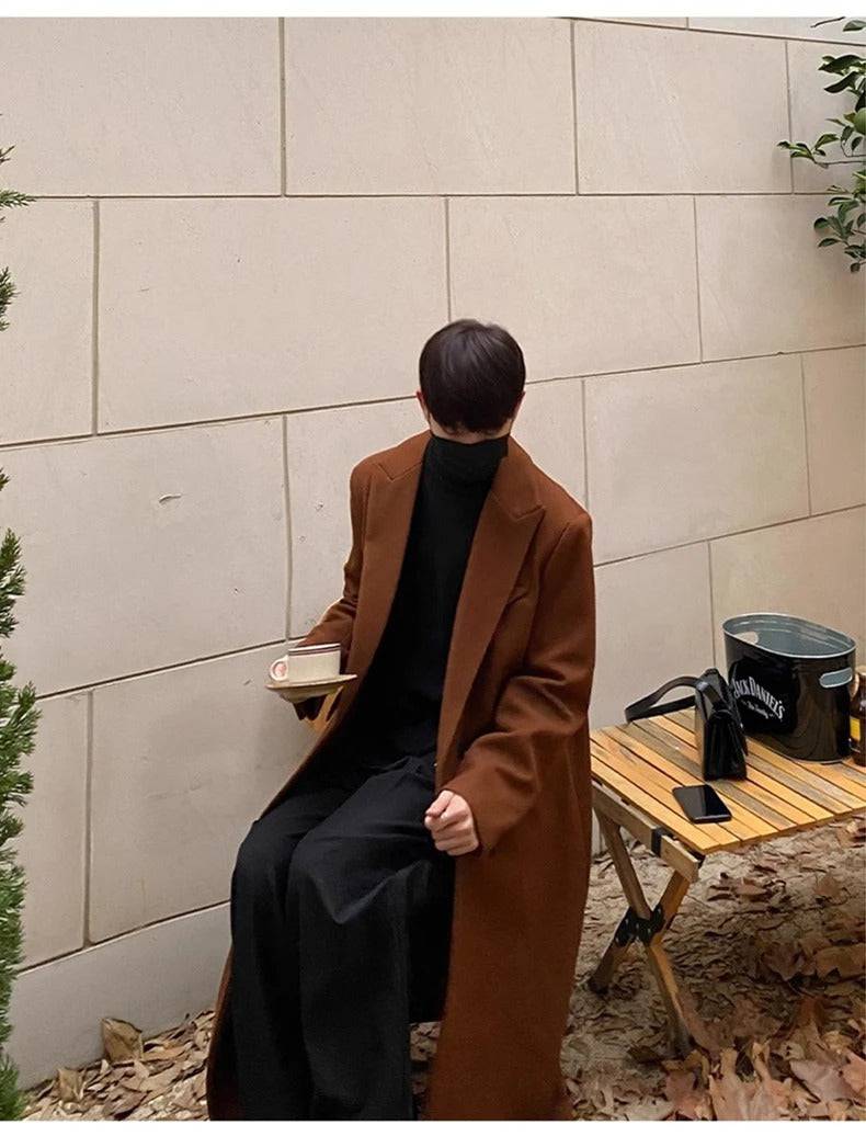 Homem com sobretudo masculino longo social marrom segurando xícara, estilo casual sofisticado. Ideal para dias frios com toque europeu.