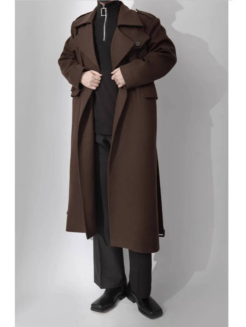 Sobretudo masculino longo de lã batida com cinto marrom, estilo europeu, usado com calça preta e bota, ideal para outono/inverno.