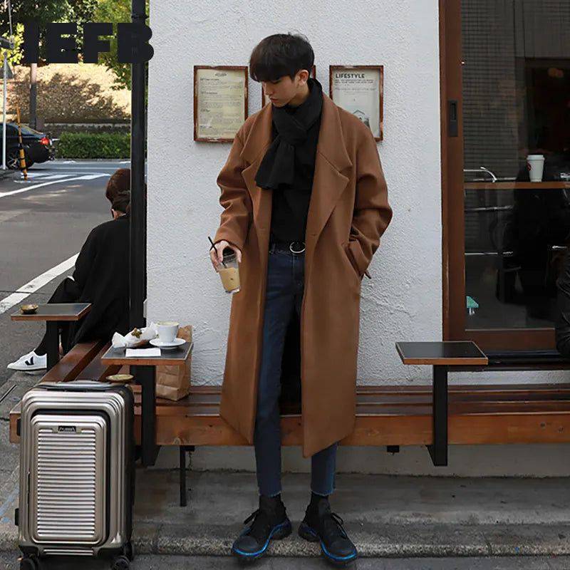 Sobretudo masculino Zellum longo de lã marrom, com cinto e 2 botões, sobre gola alta e jeans, em cafeteria urbana, evocando estilo exclusivo e conforto.