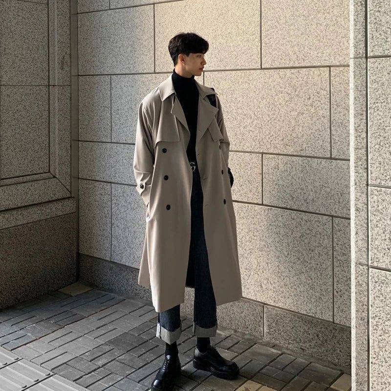 Sobretudo masculino Zellum longo bege liso, de algodão e poliéster, abotoamento duplo, sobre gola alta preta e jeans, em ambiente urbano, estilo moderno e elegante.