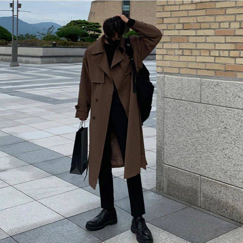 Sobretudo masculino Zellum longo marrom liso, de algodão e poliéster, sobre gola alta preta, com mochila e sacola de compras, em ambiente urbano, estilo casual e versátil.