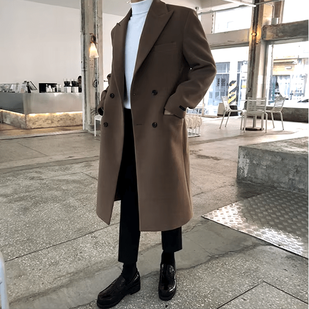Sobretudo masculino Zellum Longo Mid marrom-café, com botões duplos, sobre gola alta branca e calça preta, em ambiente moderno, estilo luxuoso.