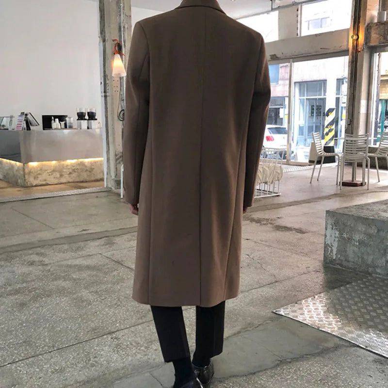 Costas do sobretudo masculino Zellum Longo Mid marrom caramelo, com corte reto, em ambiente moderno, evidenciando o caimento elegante.