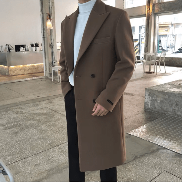 Sobretudo masculino Zellum Longo Mid marrom claro, fechamento duplo, sobre gola alta branca e calça preta, em ambiente moderno, estilo luxuoso e contemporâneo.