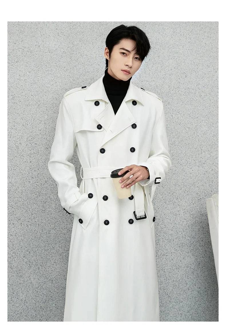 Sobretudo masculino Zellum Premium Elegante branco, longo, com cinto amarrado e botões pretos, sobre gola alta, segurando café, evocando luxo e estilo urbano.