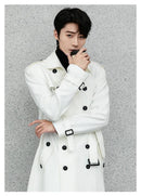 Homem com trench coat branco duplo-peito e detalhes pretos em pose elegante