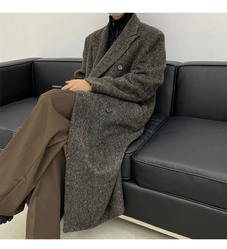 Homem sentado usando sobretudo masculino longo social cinza, peça essencial para estilo refinado e conforto térmico.